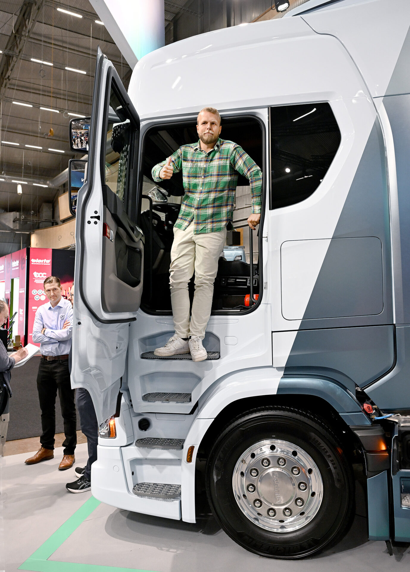 Ett kliv uppåt – mot en helt elektrifierad fordonsflotta! Falkenklev Logistiks vd Victor Falkenklev gör tummen upp för sitt rekordköp av 50 Scania ellastbilar. 